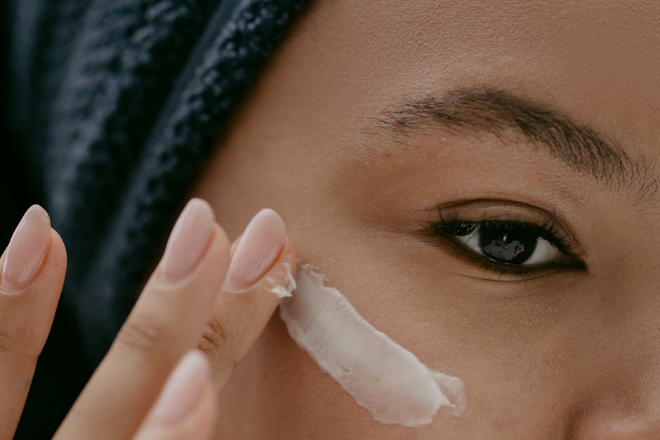 Extreme close-up of a woman applying cream to her cheek for healthy skin care