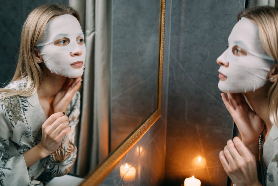 Woman applying a hydrating sheet mask while looking in the mirror, creating a serene and relaxing ambiance